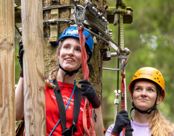 Eine Mitarbeiterin pr�ft den Sitz der Kletterausr�stung bei einem Kind